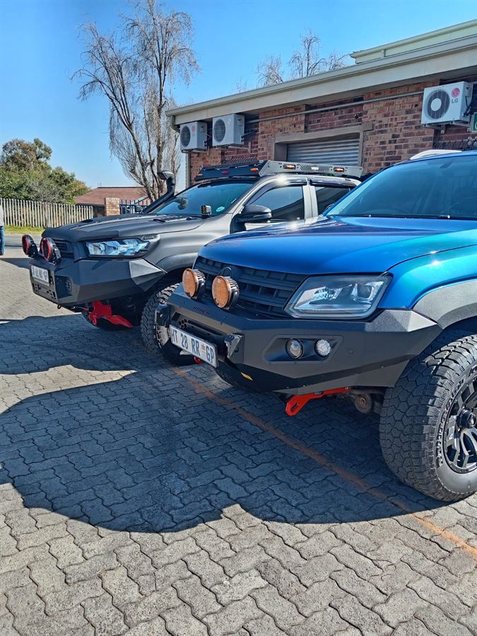 Two double-cab bakkies with replacement front bumpers and driving lights