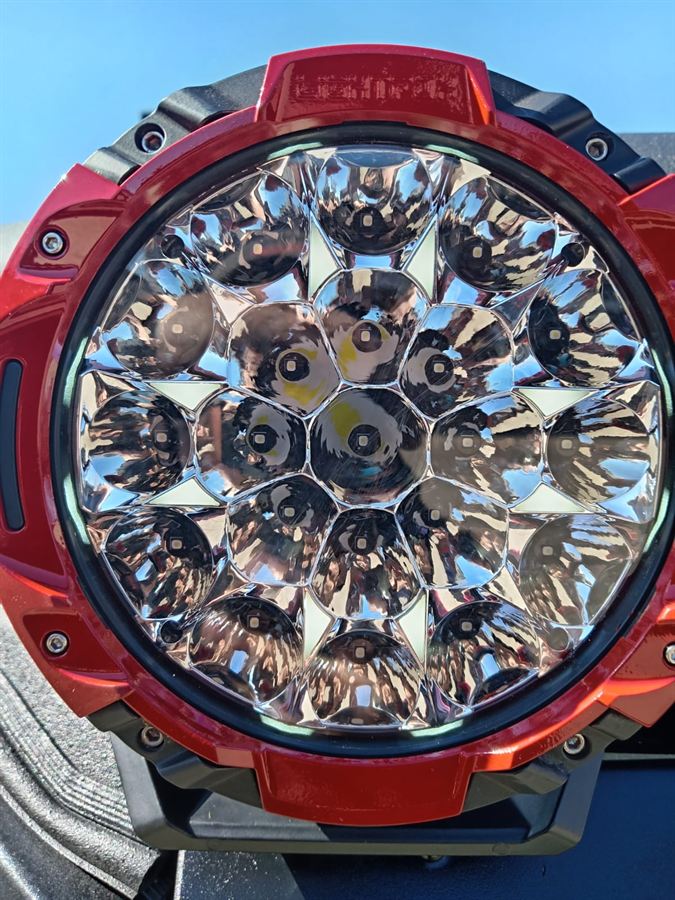 Close-up of a round multi-LED driving light with a red housing